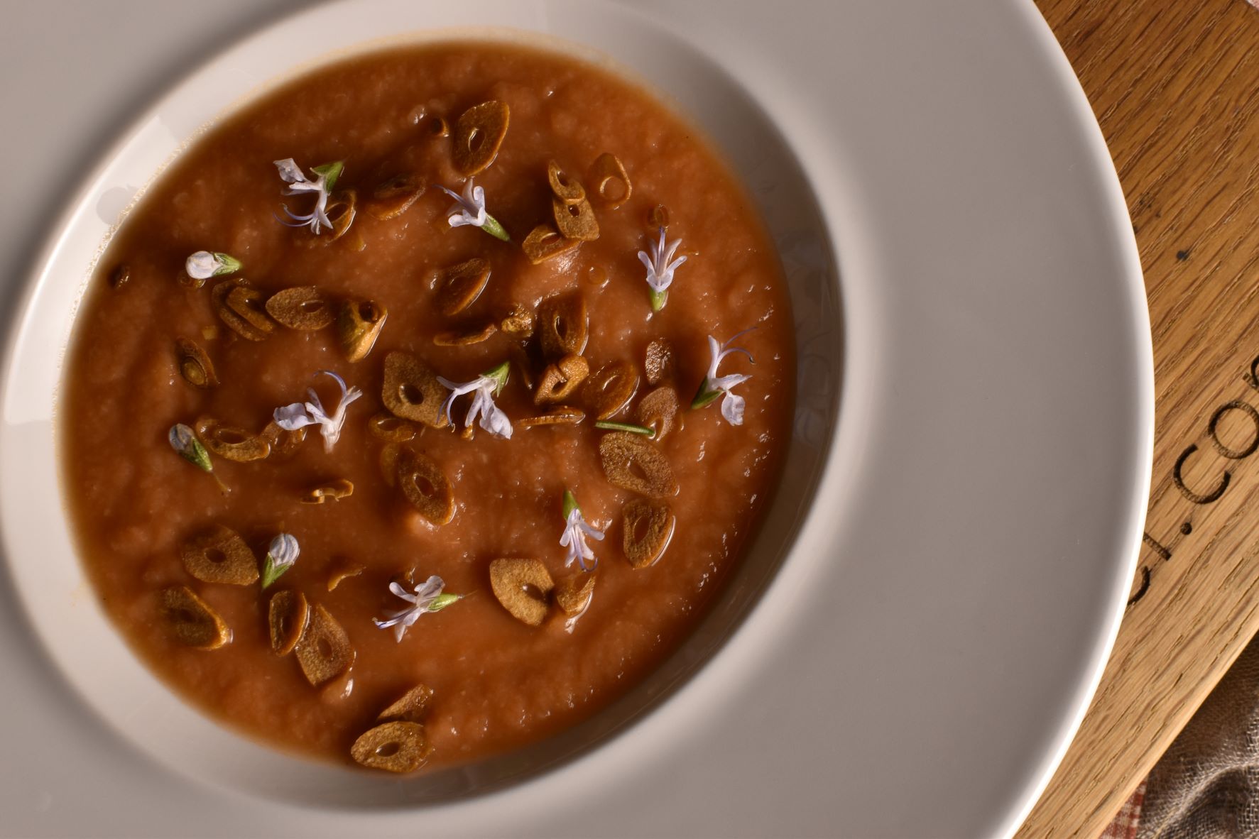 Cold tomato soup with “burnt garlic” and rosemary flowers